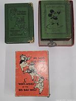 Two green book-shaped tin banks and orange cardboard box visible