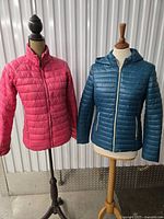 Both jackets on mannequins: left pink Jackson Hole, right teal Guess