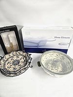 Group shot of serveware items including boxed baking dish, boxed knife, stacked bowls in rack, covered bowl