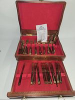 open wooden box showing two tiers of cutlery and care sheet