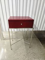 Closed red jewelry box on chrome stand, full view