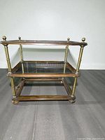 front view of the three-tier console table showing wood frame, brass posts and glass shelves