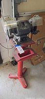 Full view of Buffalo bench grinder mounted on red pedestal stand