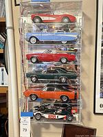 Front view of acrylic case with six die-cast cars visible