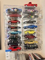 Full view of acrylic case showing arrangement of diecast cars and red pickup on top