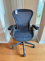 Front view of blue mesh office chair showing seat, back, armrests, and five-star base