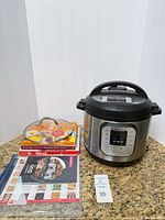 Overall lot showing Instant Pot cooker, accessories, cookbooks, manual