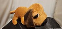 Side view of brown dachshund plush lying on black surface