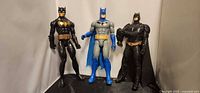 Three Batman action figures standing side by side