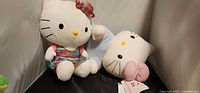 Both Hello Kitty plush toys side by side showing outfits and size