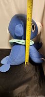 Side view of Popplio plush with measuring tape showing height