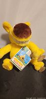 Front view of yellow Grimm plush with hangtag and suction cups visible