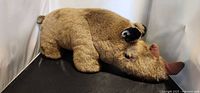 Full view of tan-brown rhinoceros plush lying on side