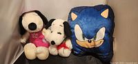 Group shot of both Snoopy plush toys and Sonic cushion
