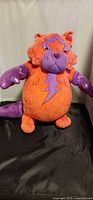 Front view of orange and purple plush cat