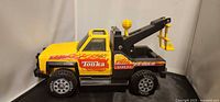 Left side view of Tonka tow truck showing cab, decals, tires