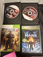 Open black case holding Gears of War and Gears of War 2 discs; closed Gears of War 3 and Mass Effect cases visible