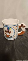 Mug front showing Zeddy graphic, paw prints, sculpted handle visible