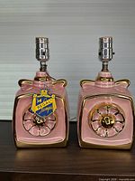 Front view of both pink and gold ceramic telephone lamps with Regal tag