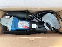 Angle grinder with handle, guard and cord inside box