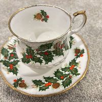 Teacup on saucer showing holly design and gold trim