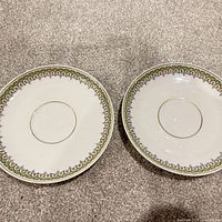 Front view of both matching saucers showing decorative border
