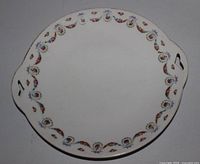 Top view of round porcelain plate showing floral rim and two cut-out handles