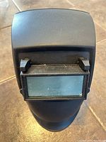 Front view of black welding helmet showing closed viewing window