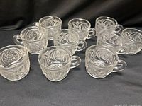 Group of nine clear pressed glass punch cups showing pattern and handles