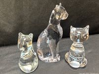 Front view of three clear glass cat paperweights