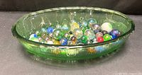 Side view of green glass bowl filled with assorted marbles