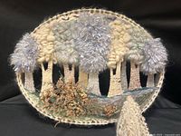 Front view of oval woven fiber art showing full design and fringe