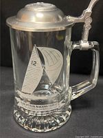 Full view of clear glass stein showing etched sailboat, handle, and pewter lid
