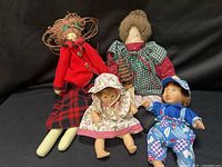 Group of four visible dolls on black backdrop showing sizes and outfits