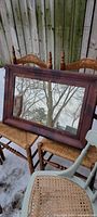 Front view of rectangular wood framed mirror reflecting outdoor scene