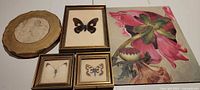 Group shot of five items: three gold framed butterflies, round sketch, floral canvas