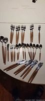 Full assortment of teak-handled cutlery laid out on table