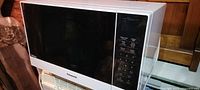 Front view of white Panasonic microwave with black door and control panel