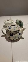 Front view showing teapot, lidded bowl, frog figurine