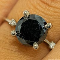 Ring on finger showing black diamond and prongs