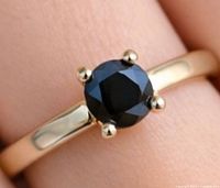 Top view of yellow-gold ring showing round black diamond in prong setting