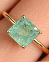 Top view of emerald ring on finger showing stone color and setting