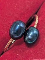 close-up of two dyed oval pearls on ring