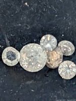 Close-up of six loose diamonds on black background