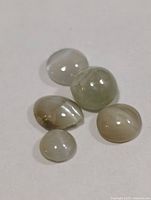 Five cat’s eye cabochon gemstones on neutral background
