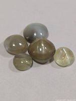 Five cat's eye cabochon gemstones on light background
