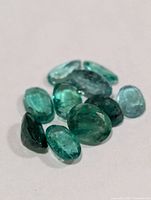 close-up of nine loose emeralds on white background
