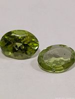 Two oval green peridots on white background