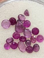 Cluster of loose rubies on white pad showing variety of cuts and color