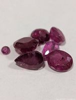 Six loose rubies on white surface showing cuts and color